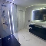 Cuarto de baño reformado con lavabo suspendido y azulejos oscuros modernos