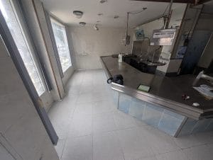 Interior de un antiguo comercio de alimentación con mostrador de acero inoxidable antes de su reforma en Burgos capital