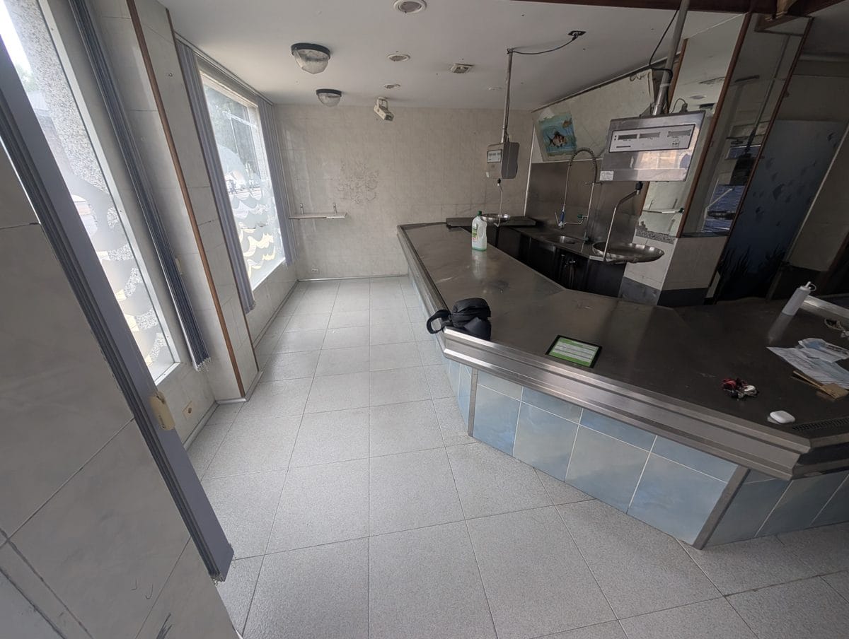 Empresas de reformas en Burgos - Reformas de baños, cocinas y tejados Interior de un antiguo comercio de alimentación con mostrador de acero inoxidable antes de su reforma en Burgos capital